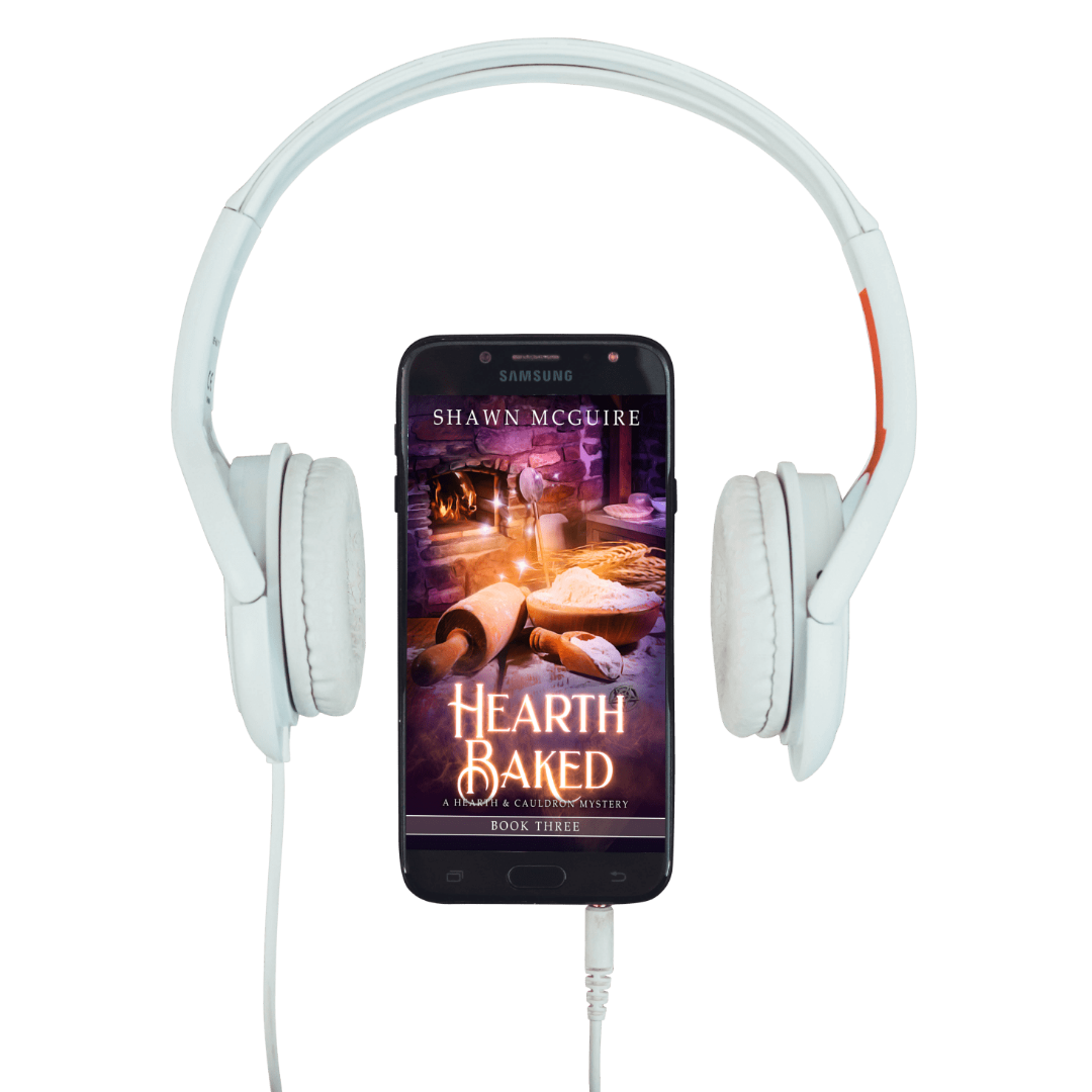 White headphones with a smartphone displaying 'Hearth Baked' by Shawn McGuire