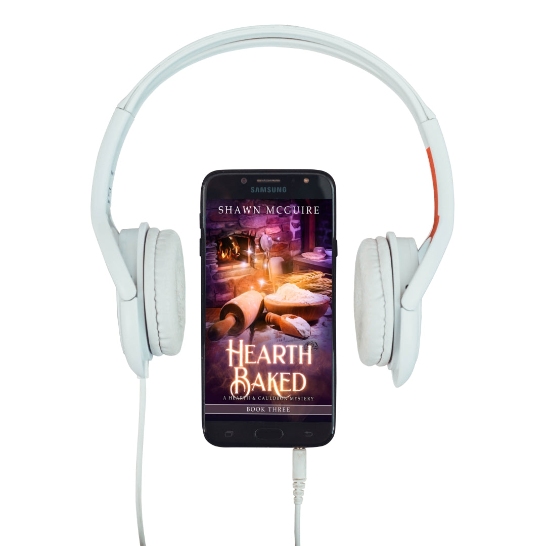Audiobook cover on cellphone of Shawn McGuire’s witch cozy midlife mysteries with a fireplace in background and large rolling pin.