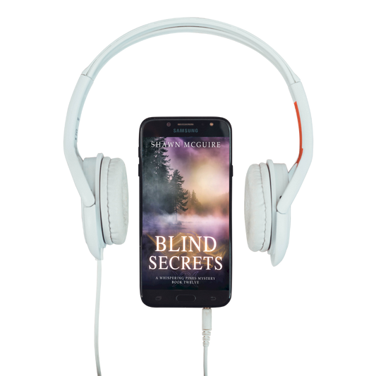 Audiobook cover on cellphone of Shawn McGuire's cozy murder mystery series set in Whispering Pines, featuring a lake shrouded in fog.