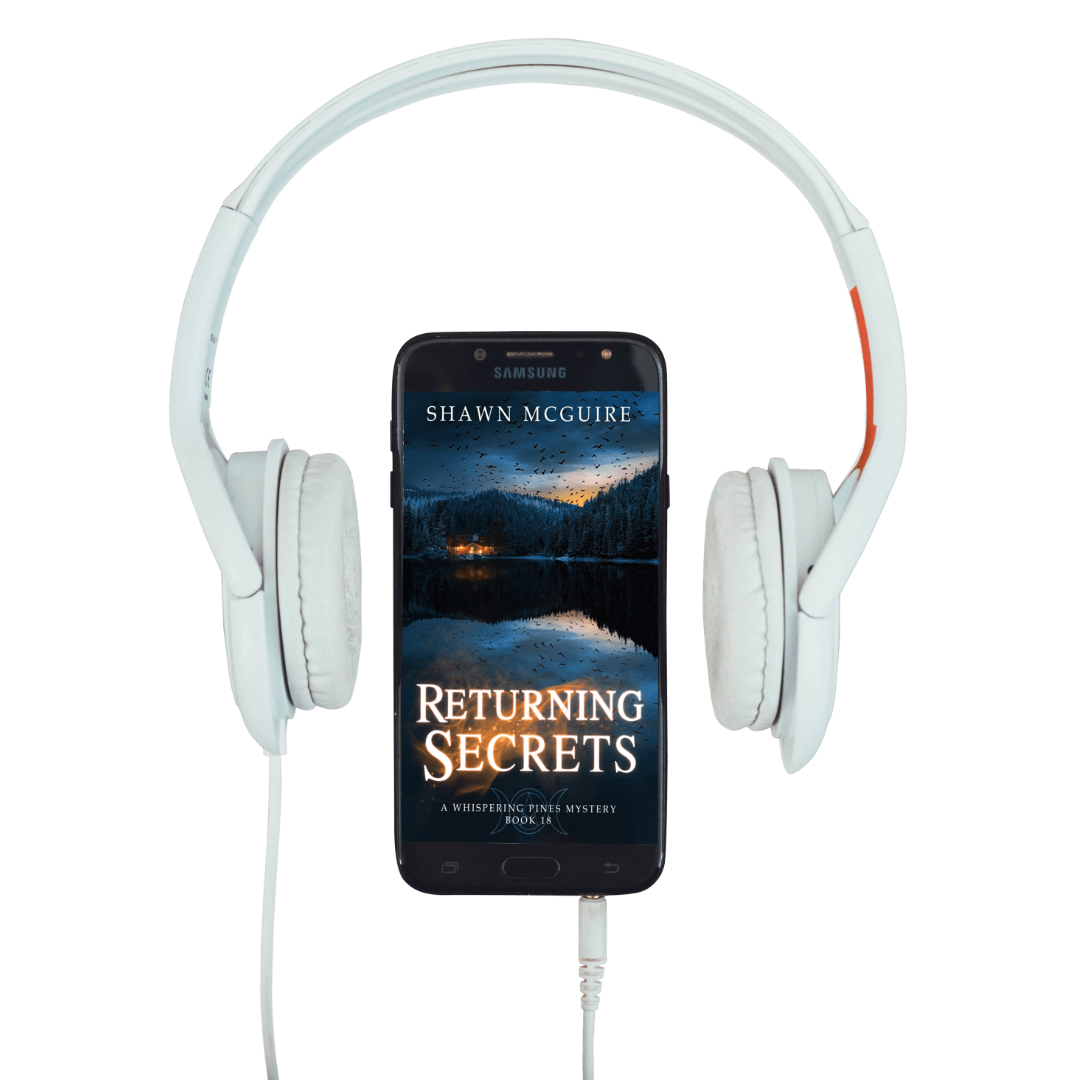 White headphones with a phone displaying 'Returning Secrets - A Whispering Pines Mystery, Book 18' by Shawn McGuire