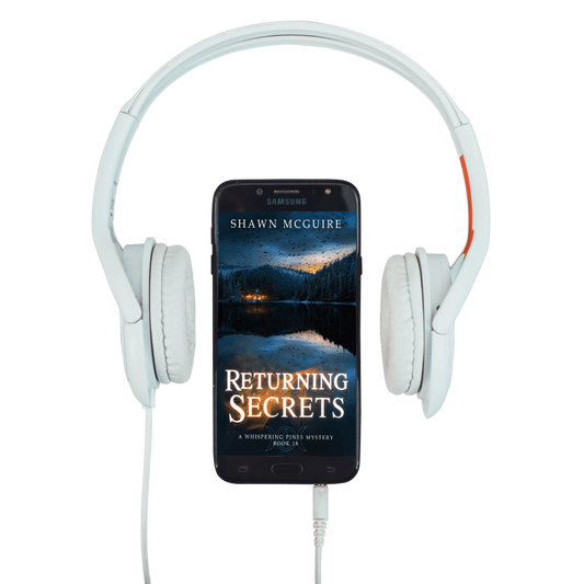 White headphones with a phone displaying 'Returning Secrets - A Whispering Pines Mystery, Book 18' by Shawn McGuire