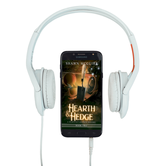White headphones with a smartphone displaying 'Hearth & Hedge' book cover.