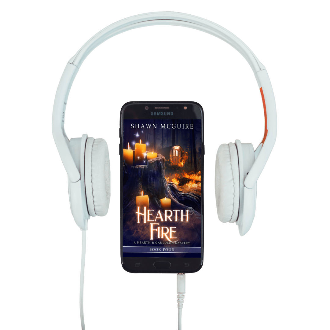 White headphones with a smartphone displaying 'Hearth Fire' by Shawn McGuire