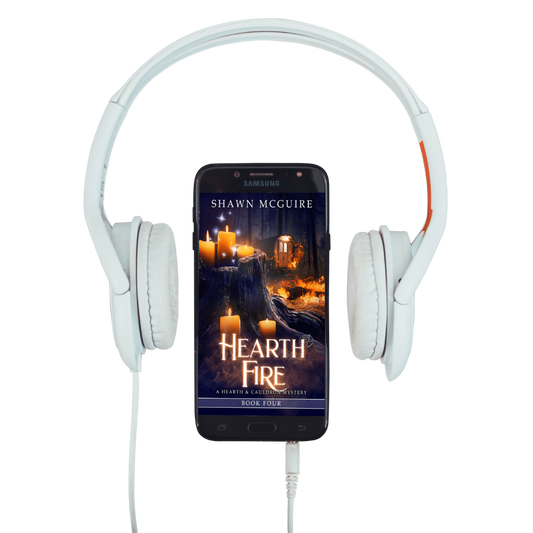 White headphones with a smartphone displaying 'Hearth Fire' by Shawn McGuire