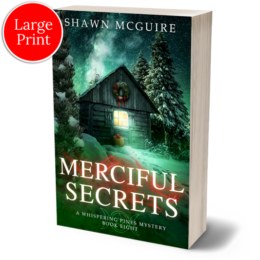 Large print paperback cover of Shawn McGuire's cozy murder mystery featuring a cabin in the woods during Yule.