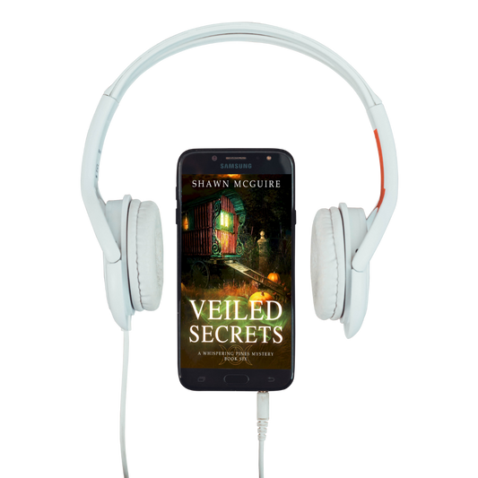 Audiobook cover on cellphone of Shawn McGuire's cozy murder mystery featuring a fortune teller’s wagon and Halloween pumpkins.