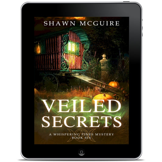 E-book cover on e-reader of Shawn McGuire's cozy murder mystery featuring a fortune teller’s wagon and Halloween pumpkins.
