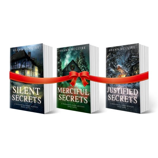 Paperback covers of Shawn McGuire’s 3-book cozy murder mystery series collection books 7-9 with a gift bow.